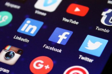 Close-up of a smartphone screen showing various social media app icons such as Facebook and Twitter.