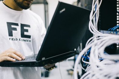 Crop focused Asian engineer in white shirt using modern netbook while working with hardware